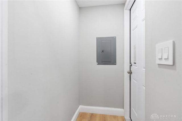 hall with electric panel, baseboards, and light wood-style flooring