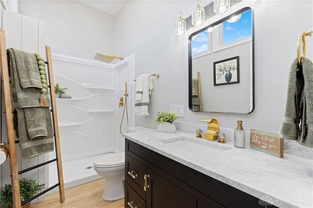 full bath with vanity, wood finished floors, a shower stall, and toilet