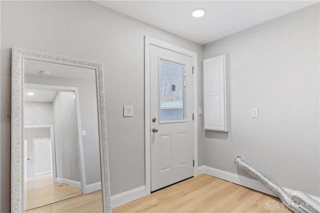 doorway featuring baseboards and light wood-style floors