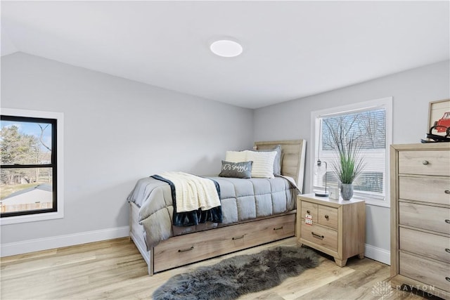 bedroom with baseboards, lofted ceiling, and light wood-style floors