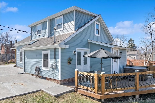 rear view of house featuring french doors, roof with shingles, and a deck