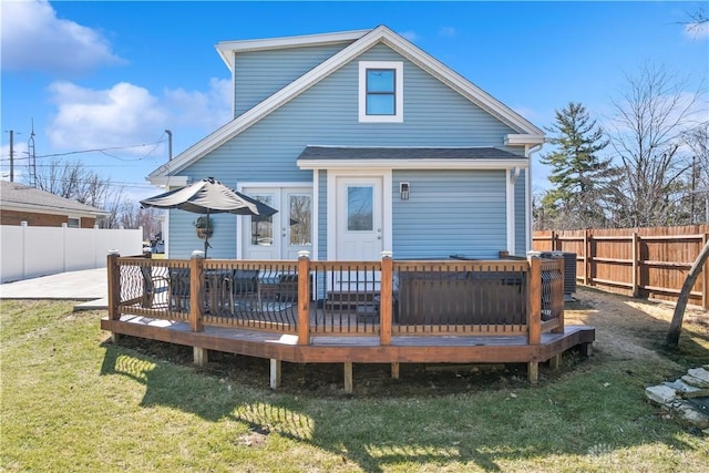 rear view of property featuring a lawn, a wooden deck, and a fenced backyard