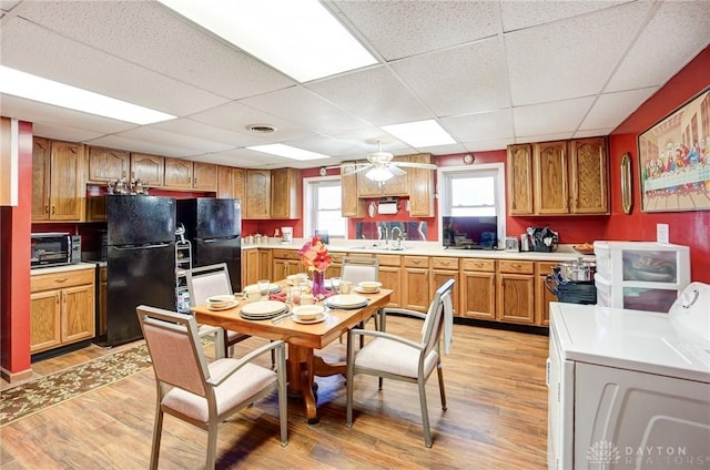 kitchen featuring light wood finished floors, washer / dryer, freestanding refrigerator, and a sink