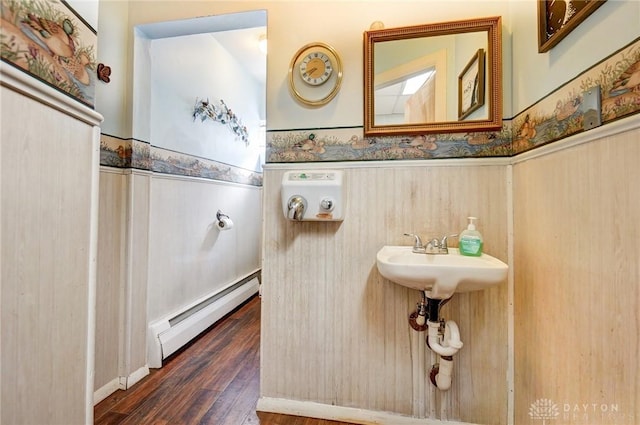 bathroom featuring a wainscoted wall, a sink, wood finished floors, and a baseboard radiator