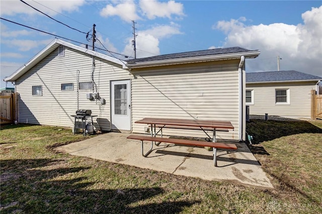 rear view of property featuring a patio area, a yard, and fence