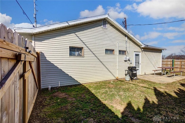 back of property with a patio, a fenced backyard, and a lawn