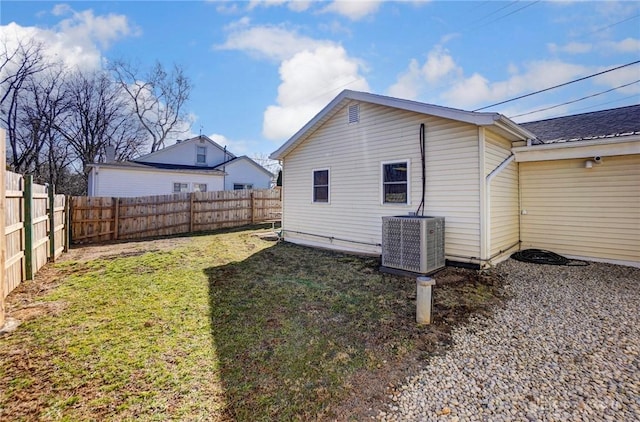 back of property with a yard, central AC, and a fenced backyard