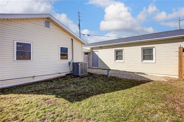 back of house with central air condition unit and a yard