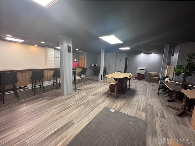 interior space with a wall mounted air conditioner, visible vents, a bar, and wood finished floors