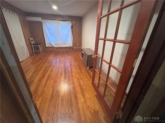 spare room featuring an AC wall unit and wood finished floors