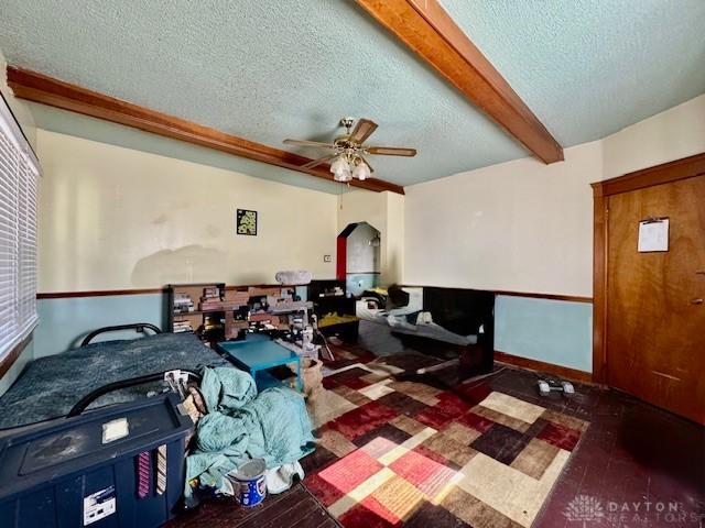 interior space featuring wood finished floors, beam ceiling, arched walkways, ceiling fan, and a textured ceiling