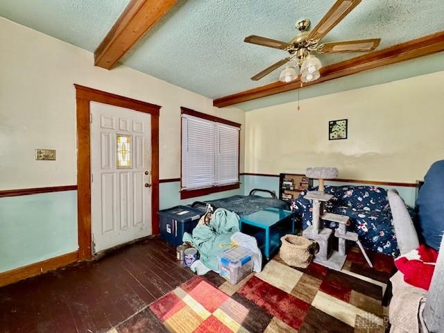 interior space with beamed ceiling, a textured ceiling, ceiling fan, and wood-type flooring