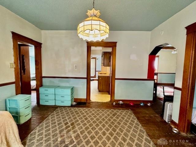 interior space featuring baseboards, arched walkways, and wood finished floors