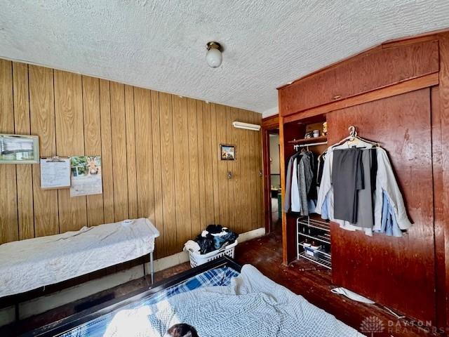 bedroom with a closet, wood walls, and a textured ceiling