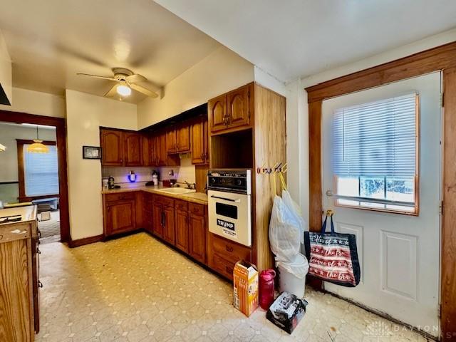 kitchen featuring oven, a ceiling fan, a sink, light countertops, and light floors