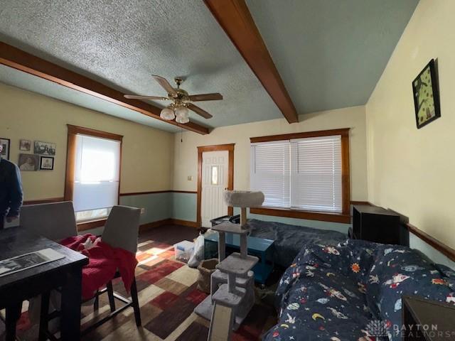 bedroom with baseboards, beam ceiling, and a textured ceiling