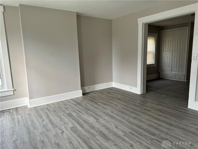 empty room with visible vents, baseboards, and wood finished floors