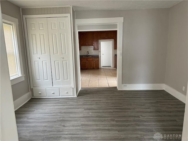 unfurnished bedroom with a closet, wood finished floors, baseboards, and a sink