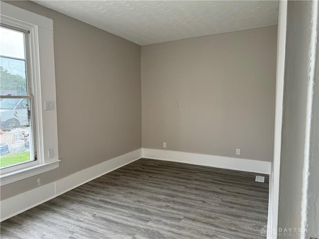 spare room with a wealth of natural light, baseboards, and wood finished floors