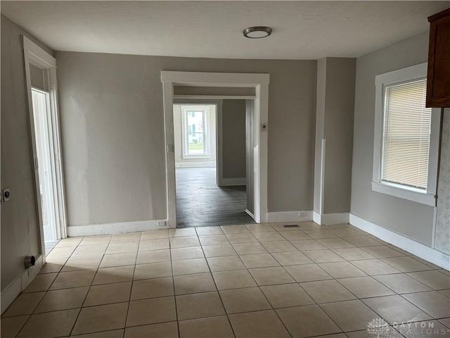 unfurnished room with light tile patterned floors and baseboards