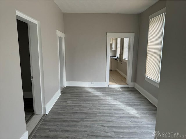 unfurnished bedroom with baseboards, ensuite bath, and wood finished floors