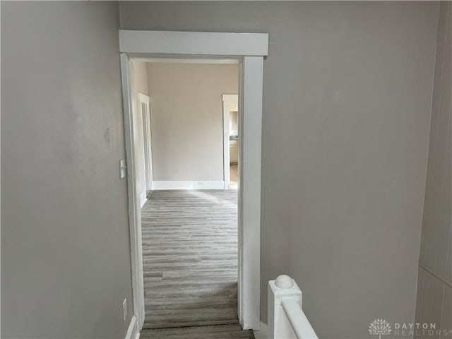 corridor with baseboards and wood finished floors