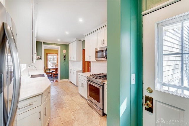 kitchen with a sink, recessed lighting, stainless steel appliances, white cabinets, and light countertops