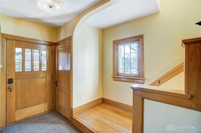 carpeted entrance foyer with baseboards and arched walkways