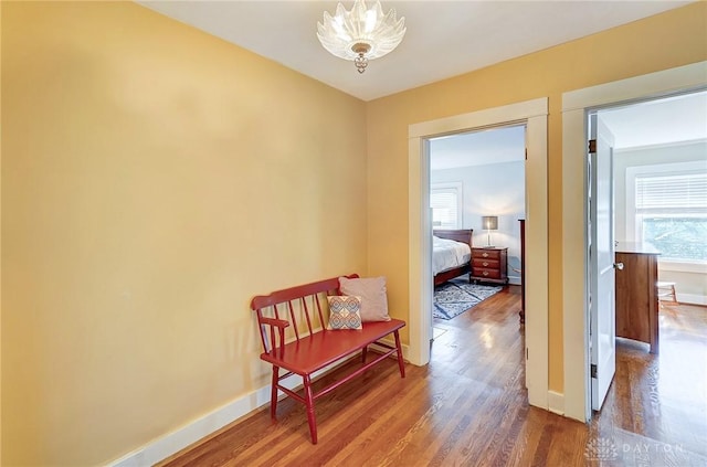 corridor featuring a notable chandelier, baseboards, and wood finished floors