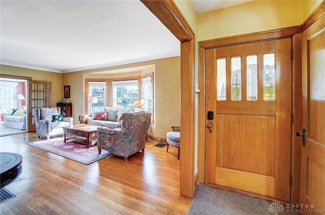 foyer entrance with crown molding and light wood-style floors