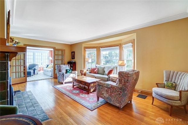 living area with visible vents, wood finished floors, and ornamental molding