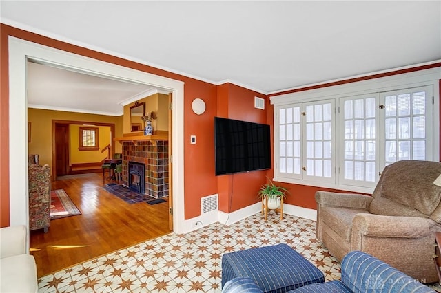 living room with visible vents, baseboards, crown molding, and a tiled fireplace