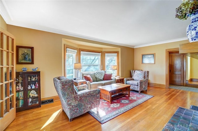 living area featuring crown molding, wood finished floors, visible vents, and baseboards