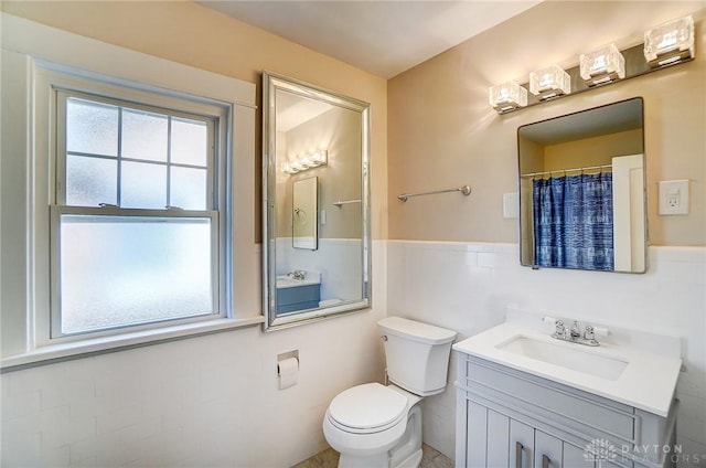 full bathroom featuring wainscoting, toilet, and vanity