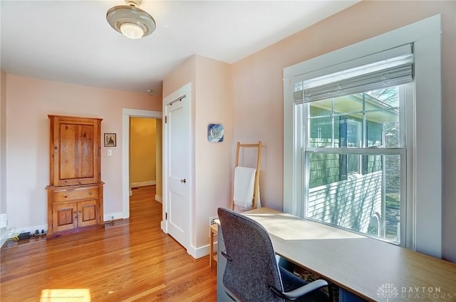 office featuring light wood-style flooring, a healthy amount of sunlight, and baseboards