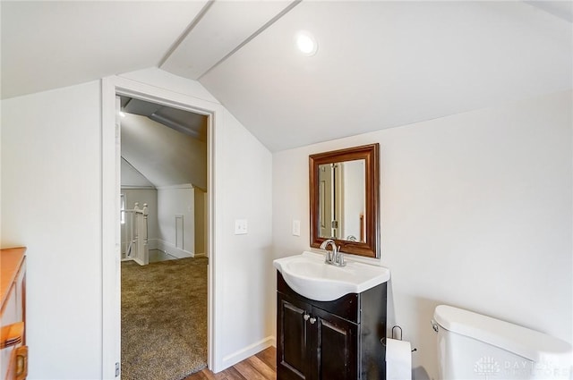 bathroom featuring vanity, vaulted ceiling, toilet, and baseboards