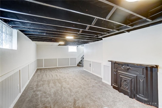 basement featuring wainscoting, stairway, and carpet flooring