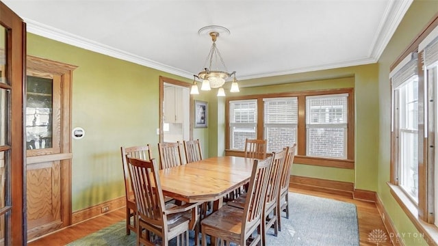 dining area featuring light wood-type flooring, a chandelier, and crown molding