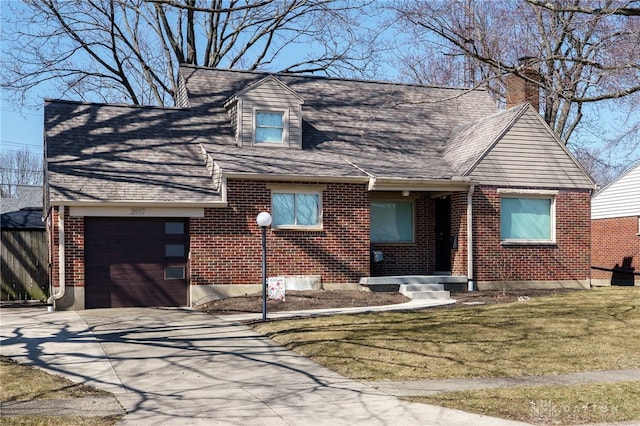 view of front of house featuring driveway, roof with shingles, a front yard, brick siding, and a chimney