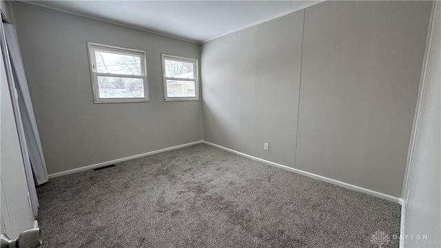 carpeted spare room featuring visible vents and baseboards