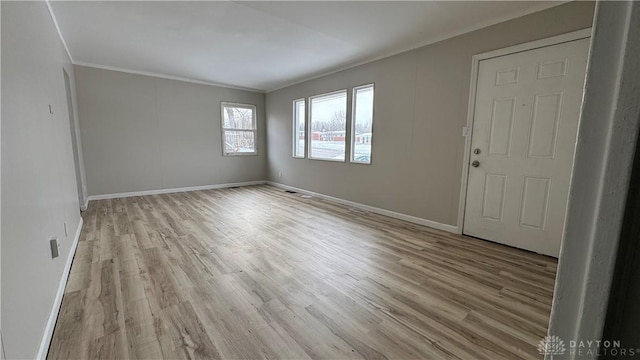 interior space featuring crown molding, light wood-style floors, and baseboards