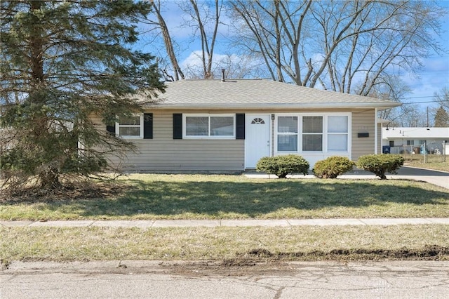 view of front of home featuring roof with shingles and a front yard