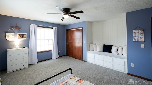 unfurnished bedroom featuring carpet flooring, a textured ceiling, baseboards, and a ceiling fan