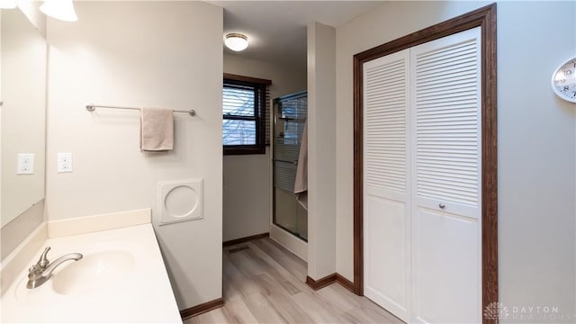 bathroom featuring vanity, wood finished floors, baseboards, a stall shower, and a closet