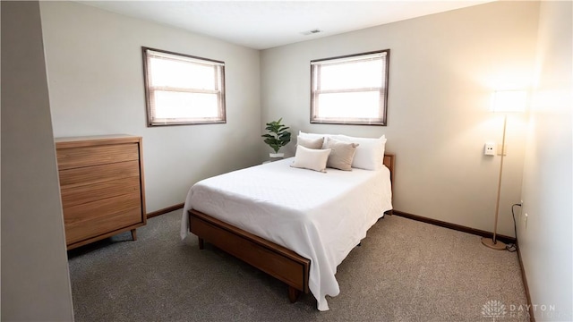 carpeted bedroom with visible vents, multiple windows, and baseboards