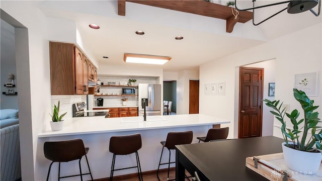 kitchen featuring open shelves, decorative backsplash, light countertops, appliances with stainless steel finishes, and brown cabinets