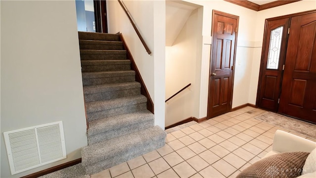 foyer featuring stairway, light tile patterned floors, baseboards, and visible vents