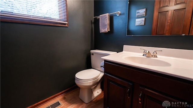 half bathroom featuring visible vents, toilet, vanity, and wood finished floors