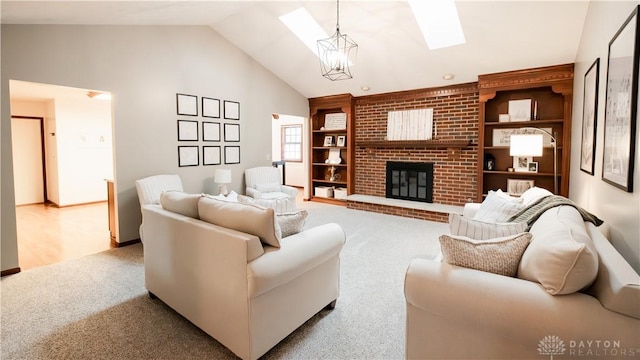 carpeted living room with built in shelves, high vaulted ceiling, a skylight, a brick fireplace, and a chandelier