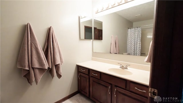 full bath with curtained shower, baseboards, and vanity